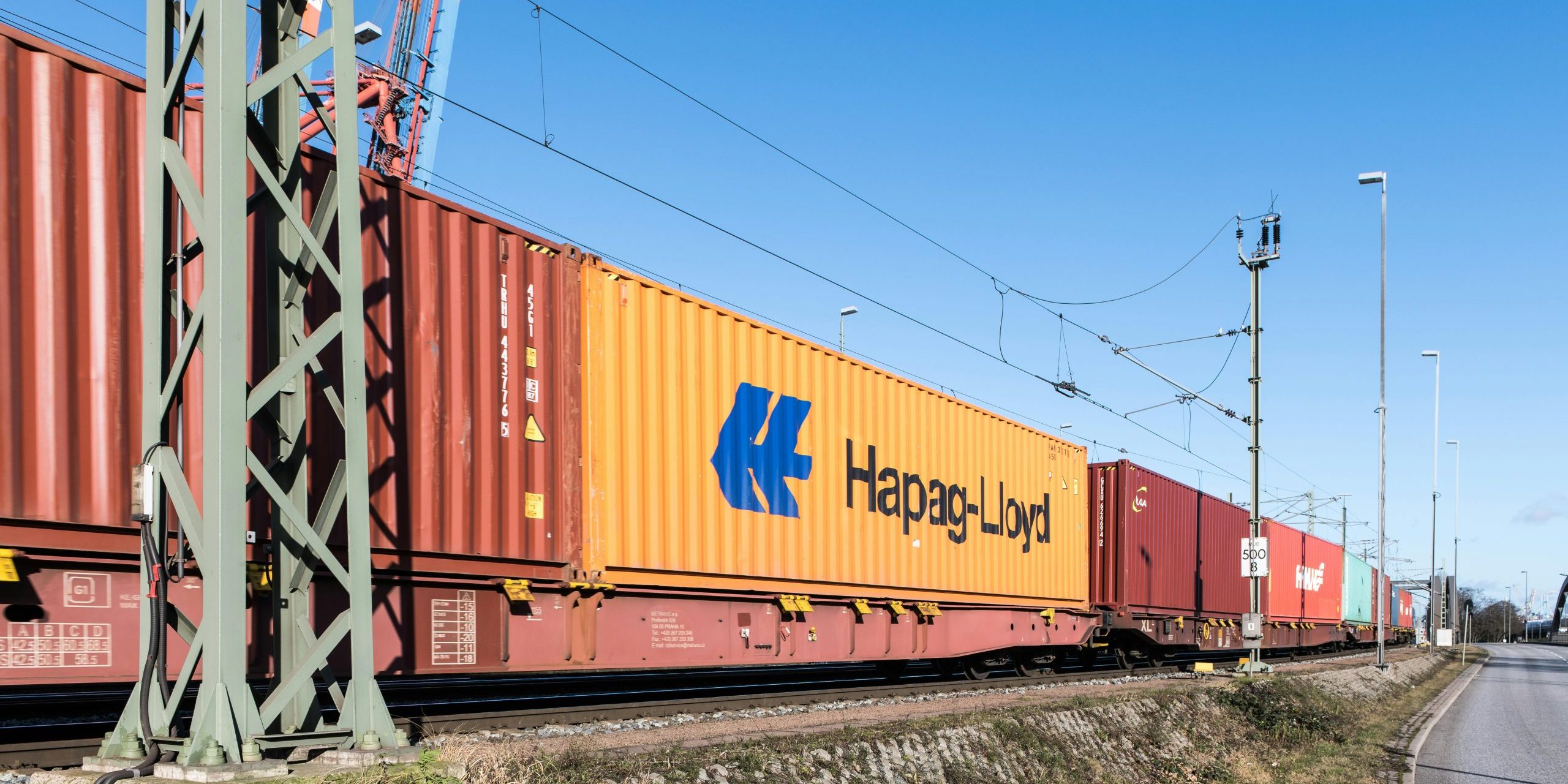 Freight train transporting containers near Hamburg harbor on a clear day.